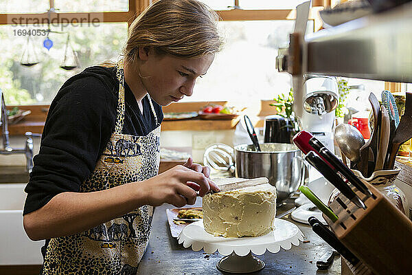 Teenager-Mädchen in der Küche Anwendung Zuckerguss auf Kuchen