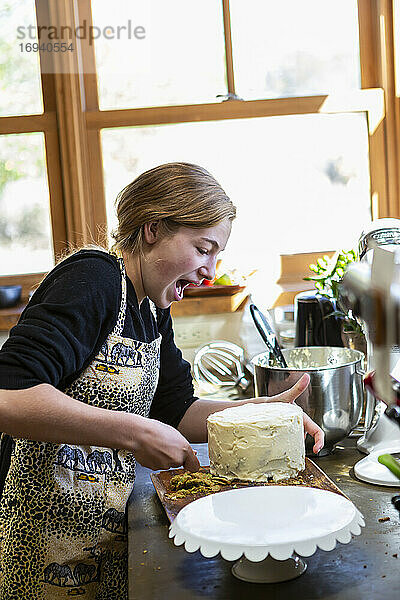 Teenager-Mädchen in der Küche Anwendung Zuckerguss auf Kuchen