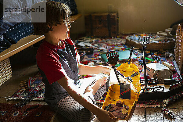 Draufsicht auf einen kleinen Jungen in seinem Zimmer  der mit seinen Spielsachen spielt