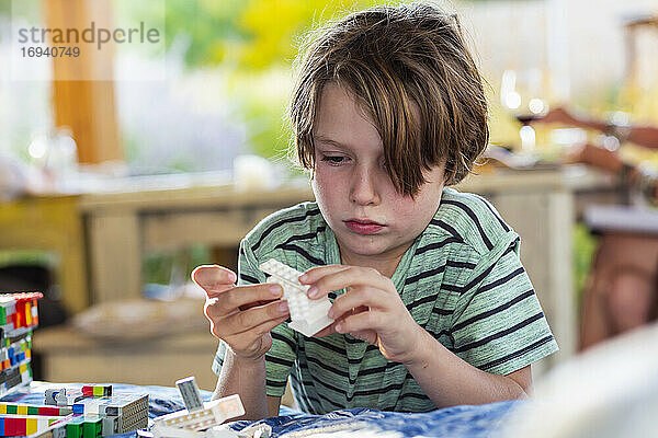 7 Jahre alter Junge spielt mit Bauklötzen auf einer Terrasse