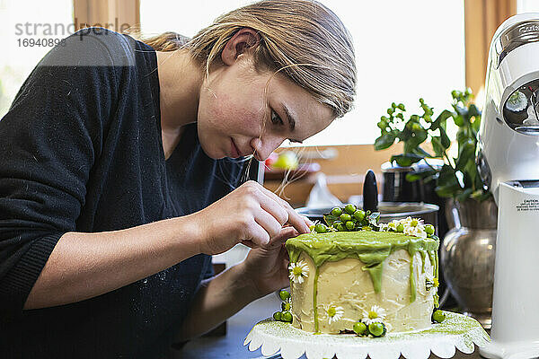 Teenager-Mädchen in der Küche Anwendung Zuckerguss auf Kuchen