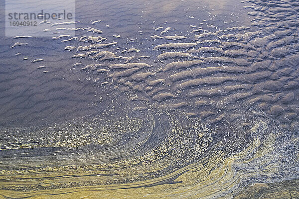 Meerwasser und Wellenmuster im Sand bei Ebbe.