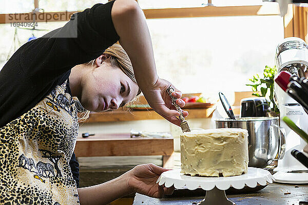 Teenager-Mädchen in der Küche Anwendung Zuckerguss auf Kuchen