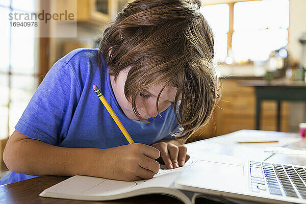 Junger Junge zu Hause schreiben und zeichnen in seinem Zeichenblock