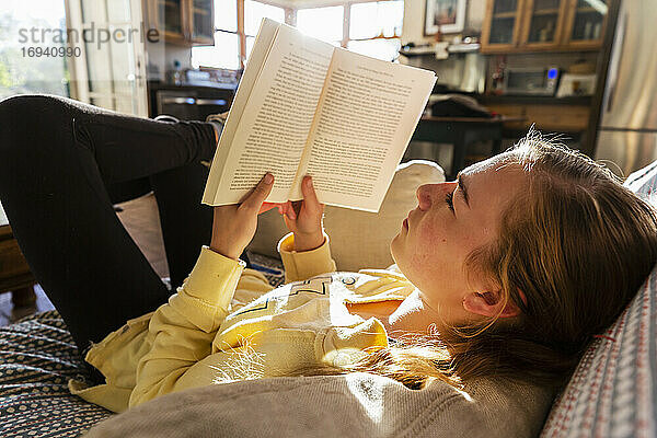 Teenager-Mädchen liest Buch zu Hause im frühen Morgenlicht