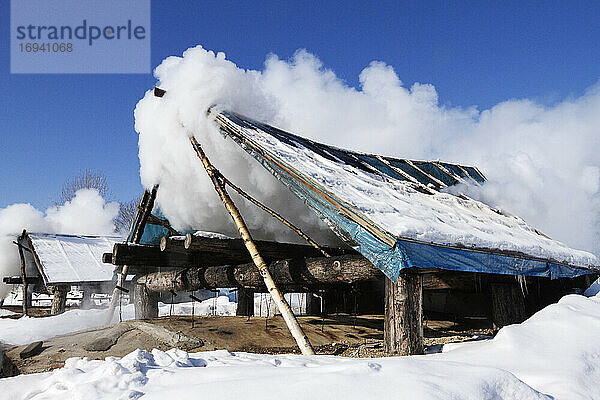 Mit Wolken bedeckte Holzhütte im Schnee.