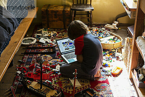 Junger Junge spielt in seinem Zimmer  schaut auf Laptop