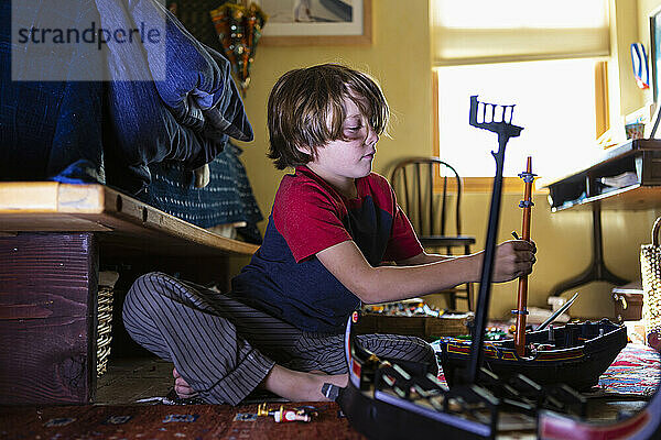 7 Jahre alter Junge spielt mit seinem Spielzeug in seinem Zimmer