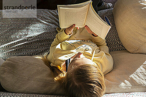 Teenager-Mädchen liest Buch zu Hause im frühen Morgenlicht