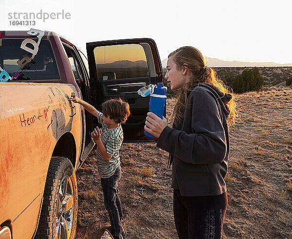 Zwei Kinder malen die Seite eines alten Pickup-Trucks