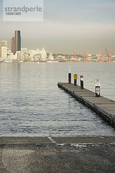 Pier ins Wasser am städtischen Ufer mit Wolkenkratzern dahinter.