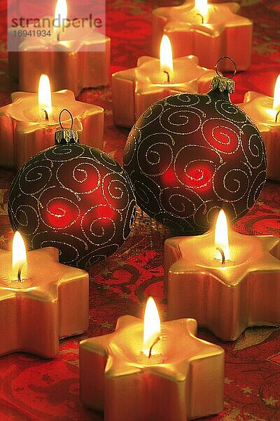 Weihnachtsdekoration mit Christbaumkugeln und sternförmigen Kerzen