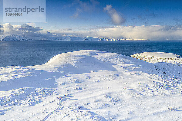 Luftaufnahme von weißen Bergen mit Schnee bedeckt  die das blaue gefrorene Meer umgeben  Hasvik  Soroya Island  Troms og Finnmark  Arktis  Norwegen  Skandinavien  Europa