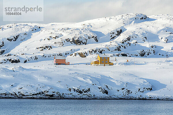 Isolierte Holzhäuser im Schnee entlang des Fjords im arktischen Winter  Oksfjord  Troms og Finnmark  Nordnorwegen  Skandinavien  Europa