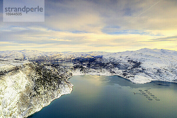 Luftaufnahme von bewölktem Himmel bei Sonnenuntergang über Fischfarmen und Berge entlang Altafjord im Winter  Troms og Finnmark  Nordnorwegen  Skandinavien  Europa