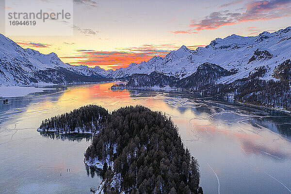 Luftaufnahme des brennenden Himmels bei Sonnenuntergang auf dem gefrorenen Silsersee und schneebedeckten Bergen  Malojapass  Kanton Graubünden  Schweizer Alpen  Schweiz  Europa