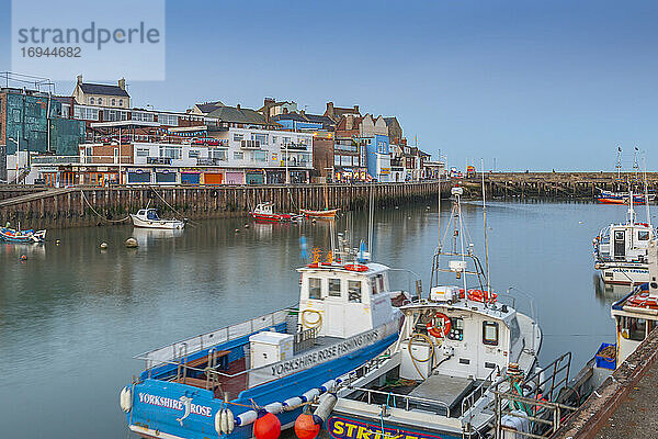 Blick auf Hafenboote und Geschäfte am Hafen in Bridlington Harbour in der Abenddämmerung  Bridlington  East Yorkshire  England  Vereinigtes Königreich  Europa