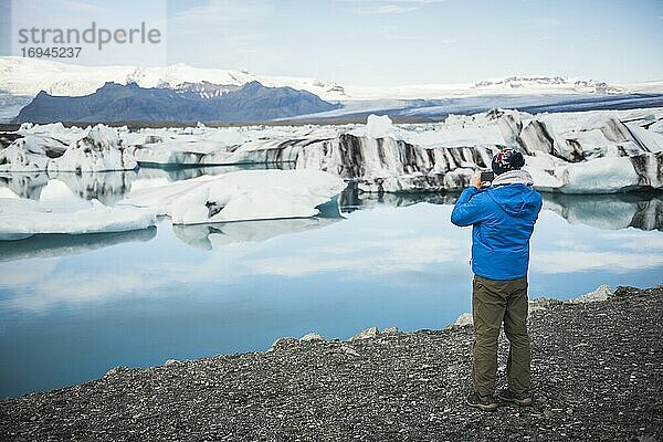 Tourist beim Fotografieren der Jokulsarlon Gletscherlagune  einem Gletschersee mit Eisbergen im Südosten Islands