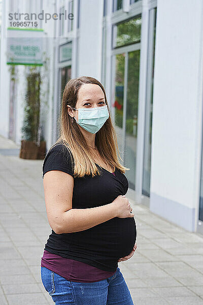 Schwangere Frau vor einer Apotheke in der Stadt  Coronakrise  (CoVID-19)  Bayern  Deutschland
