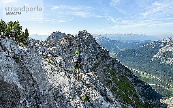 Bergsteiger klettert an einem gesicherten Klettersteig  Mittenwalder Höhenweg  Ausblick ins Isartal bei Mittenwald  Karwendelgebirge  Mittenwald  Bayern  Deutschland  Europa