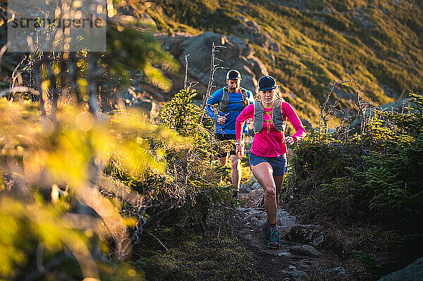 Mann und Frau beim Trailrunning bei Sonnenaufgang in den Bergen