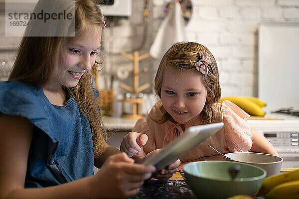 Mädchen spielt Spiel auf Tablet mit Schwester