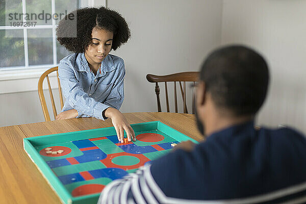 Ein zehnjähriges afroamerikanisches Mädchen spielt mit seinem Vater ein Brettspiel