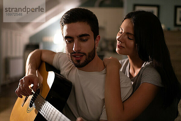 Junger Mann spielt Gitarre für Freundin
