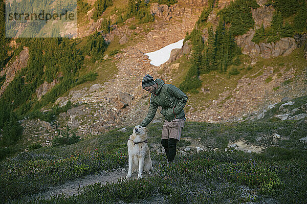 Mann streichelt Hund in den Bergen bei Sonnenuntergang