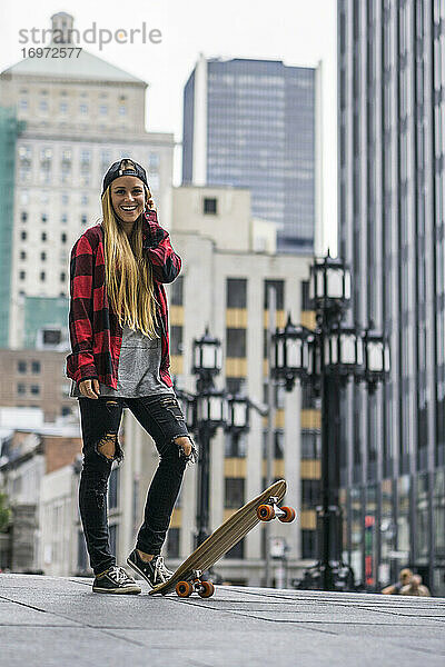 Weiblicher Millennial in städtischem Gebiet mit Skateboard bereit zu rollen ar