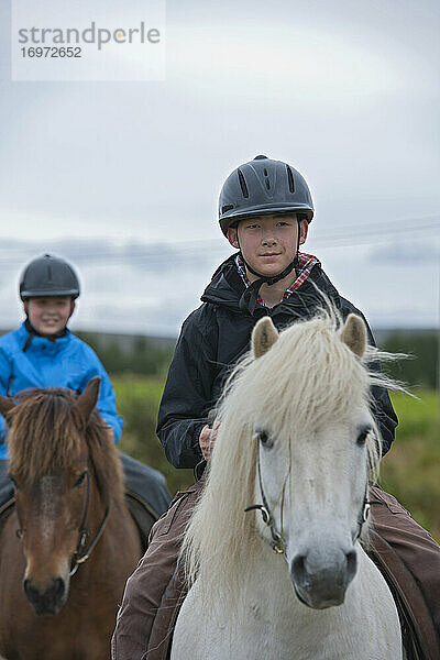 zwei Brüder reiten auf Islandpferden in abgelegener Gegend