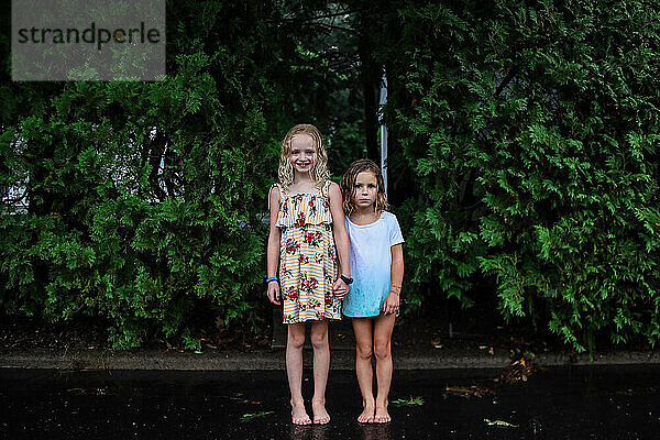 Porträt von zwei Mädchen  die im Regen stehen