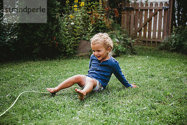 Kleiner Junge spielt in baykyard im Sommer mit Spaß sitzen auf Gras