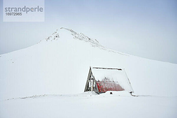 Einsames Haus in verschneitem nördlichen Terrain