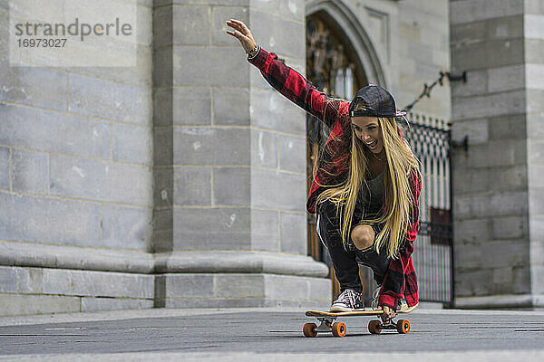 Weibliche Skateboarderin balanciert auf einem Skateboard und rollt durch die Gegend