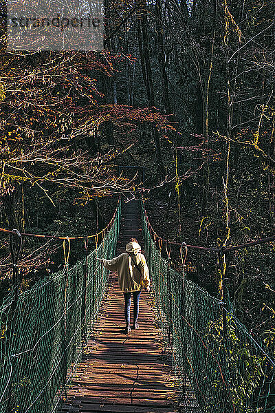 Junge Frau beim Überqueren einer Hängebrücke