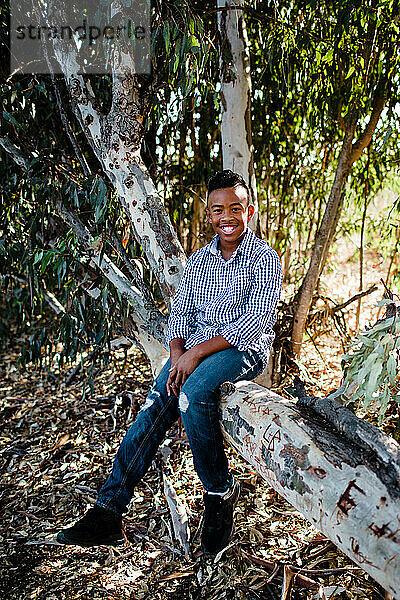 Junger Junge posiert im Baum und lächelt für die Kamera im Park in Chula Vista