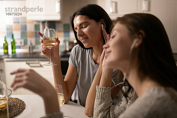 Junge Frau genießt Wein und Musik bei einem Freund