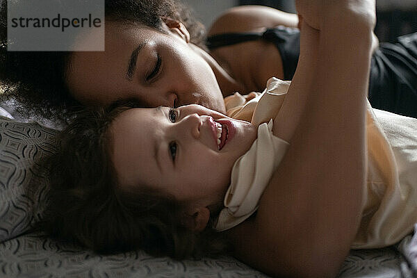 Mutter küsst Tochter auf dem Bett