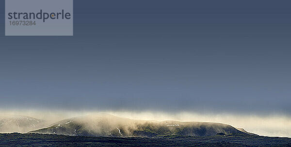 Raue nordische Berglandschaft mit Nebel und blauem Himmel