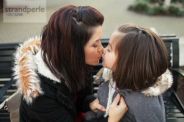 Mutter küsst ihre Tochter im Park