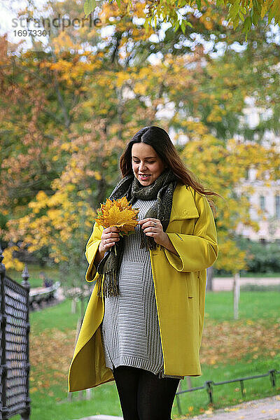 Bild einer glücklichen schwangeren Frau im Freien im Herbst.