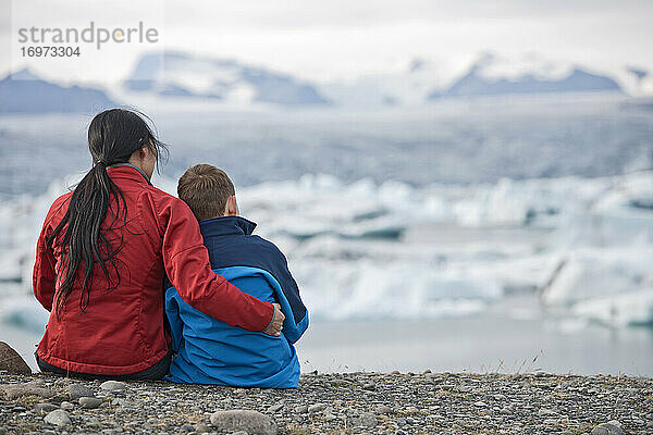 Mutter und Sohn betrachten eine Gletscherlagune in Island