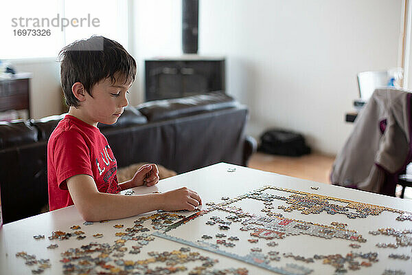 Junge setzt am Küchentisch ein Puzzle zusammen