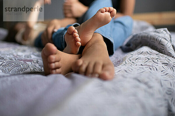 Abgeschnittene Mutter und Kind spielen auf dem Bett