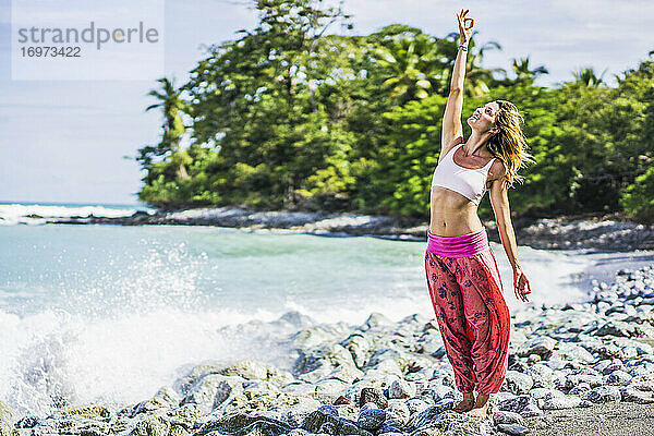 Weiblicher Yogi in spiritueller Haltung am Strand