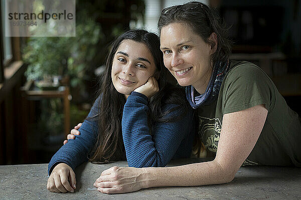 Mutter mit Arm um hübsche Teenager-Tochter  die in die Kamera lächelt