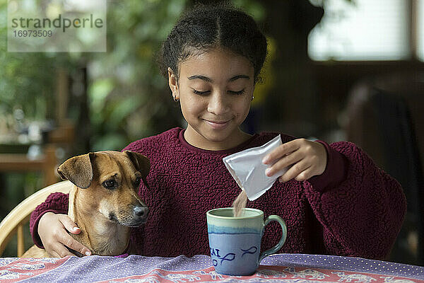 Porträt eines gemischtrassigen elfjährigen Mädchens mit Arm um einen kleinen Hund