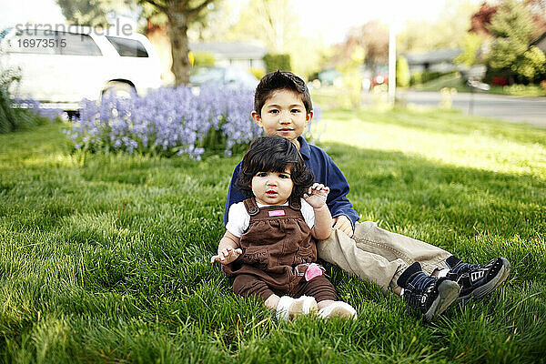 Kleiner Junge und seine kleine Schwester schauen in die Kamera  im Park