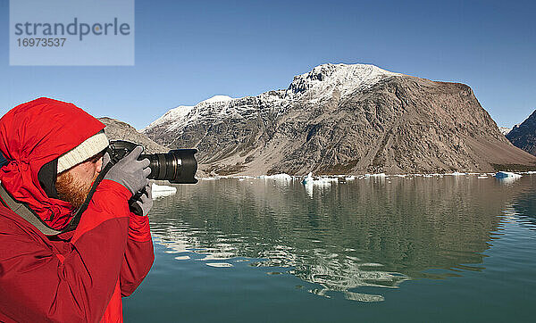 Mann beim Fotografieren mit einer digitalen Spiegelreflexkamera in Südgrönland